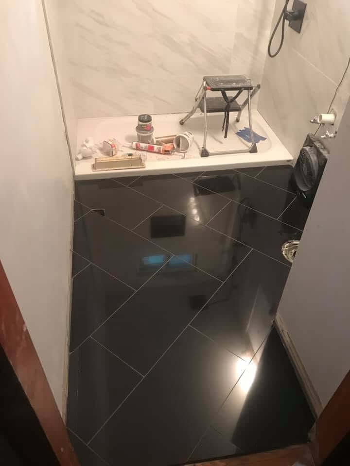 Dark large-format tile bathroom floor installation Cape Cod